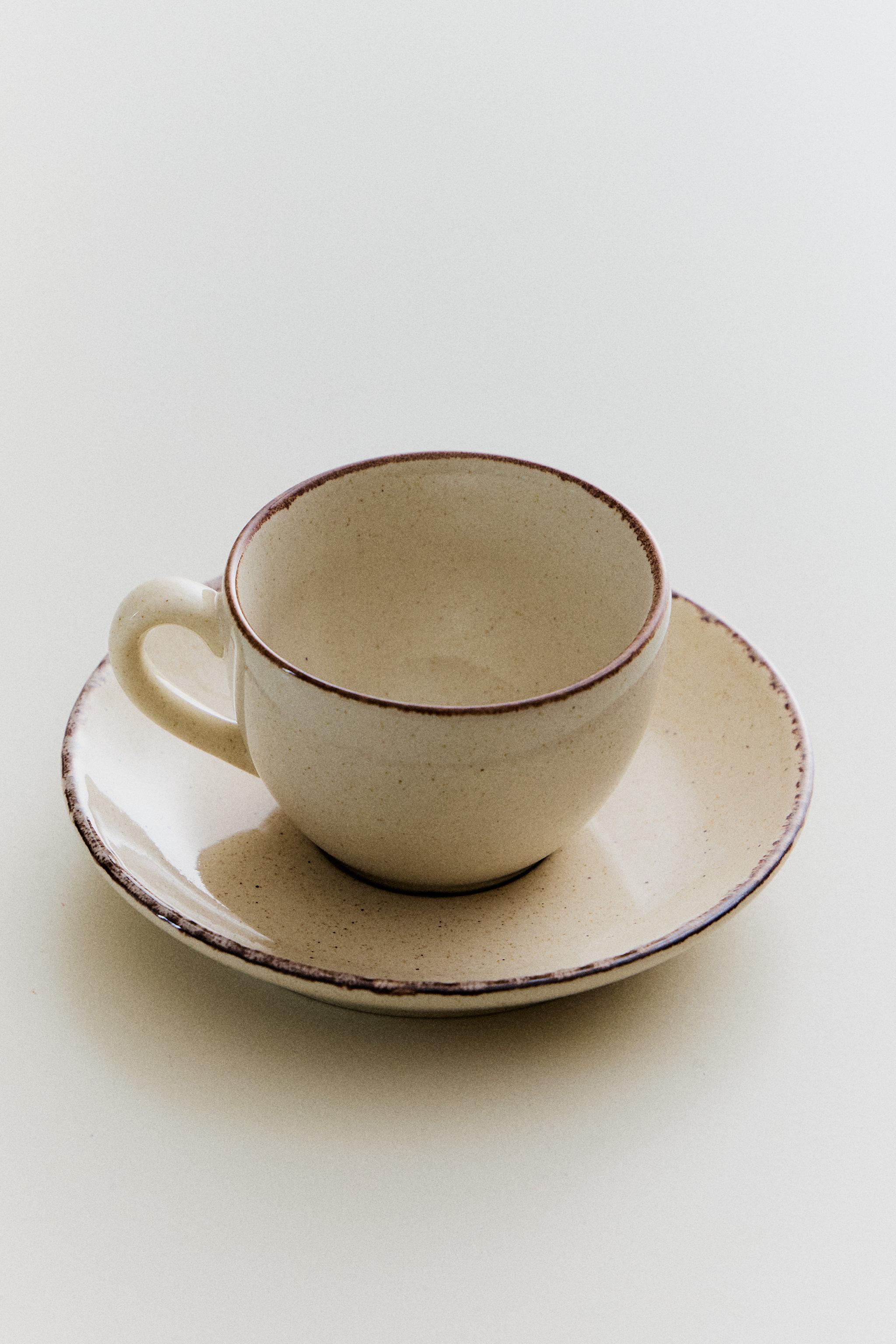 STONEWARE TEACUP AND SAUCER WITH DISTRESSED RIM